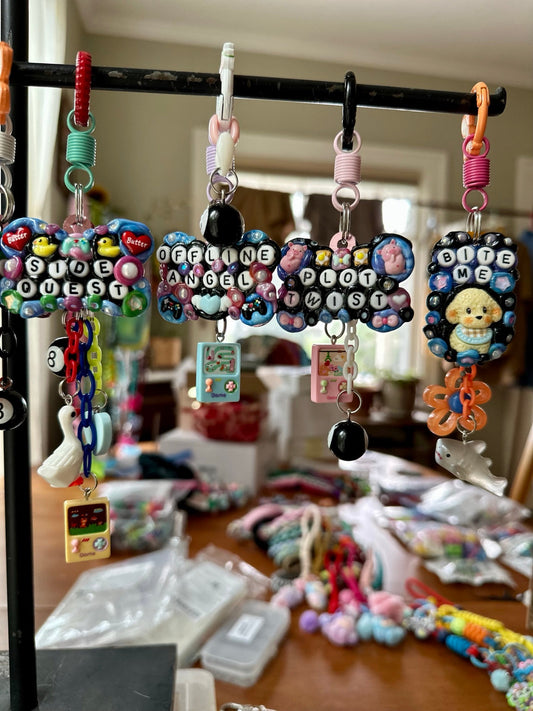 Colorful handmade Pocket Pal bag charms hanging together on a Drea Svea display