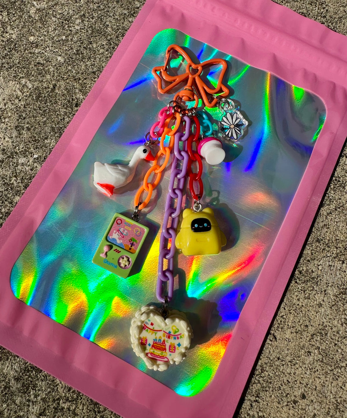 Birthday Quest Pocket Pal with bow clasp, colorful chains, goose, game charm, mushroom, yellow robot and Drea Svea acrylic tag