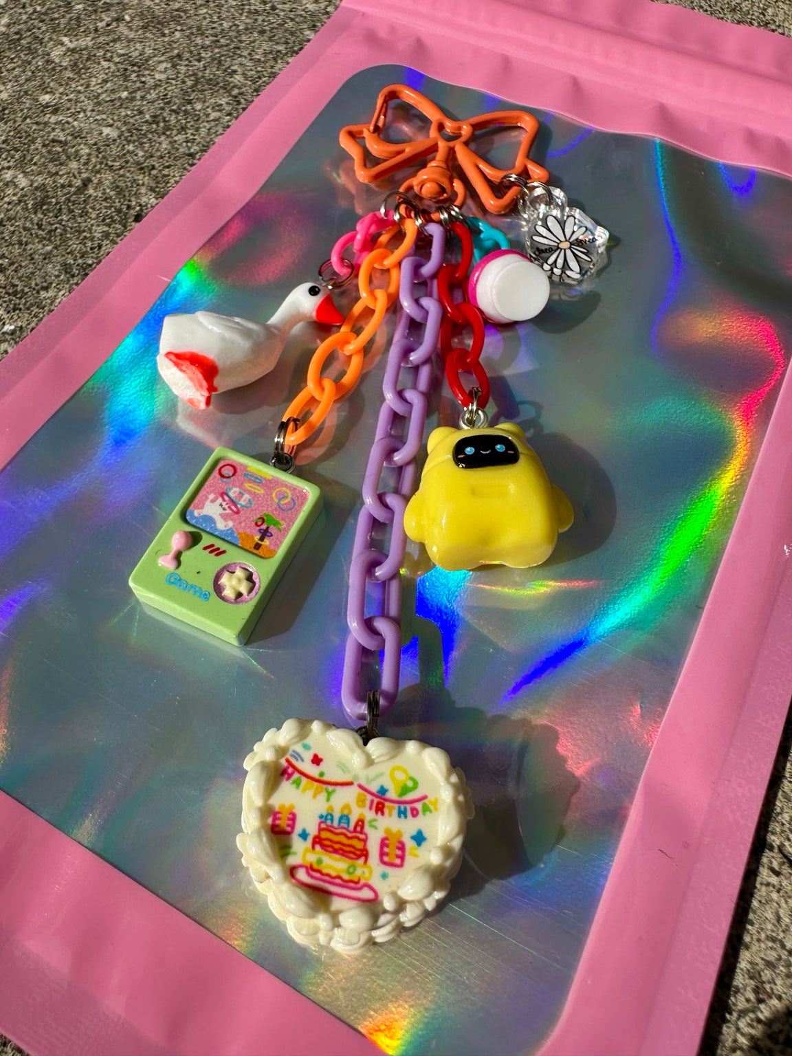 Birthday Quest Pocket Pal close-up with Happy Birthday heart, game charm, goose, mushroom and yellow robot