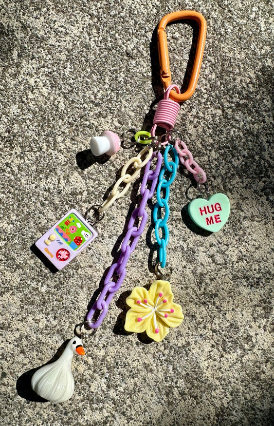 Pocket Pal bag charm with orange clasp, colorful chains, goose, yellow flower, HUG ME heart, game charm and mushroom