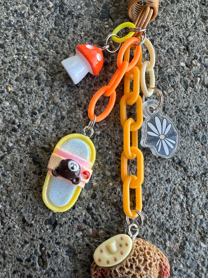 Detail of Crumb's orange chain and charms with Crumb hanging upright