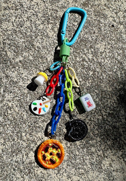 Booked and Busy Pocket Pal bag charm with pizza, cookie, mahjong tile, artist palette and mushroom charms